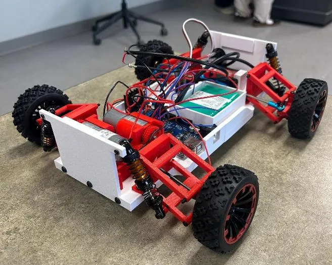 The finished RC vehicle with red 3D-printed suspension arms and exposed electronics